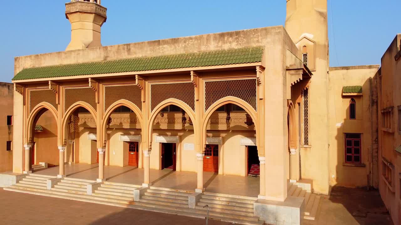 Low aerial dynamic closeup panning view of Banjul central King Fahd Mosque entrance facade on sunny afternoon