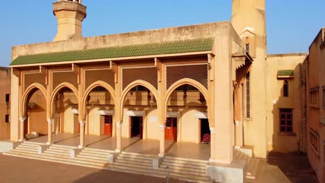 low aerial dynamic closeup panning view of banjul central king fahd mosque entrance facade on sunny afternoon