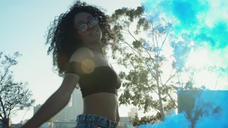 una mujer joven bailando afuera con una granada de humo al atardecer en el garaje del techo