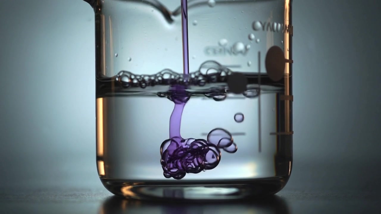 Pipeta injetando e liberando corante roxo em líquido de béquer marcado na bancada do laboratório, formando um aglomerado de gotas.