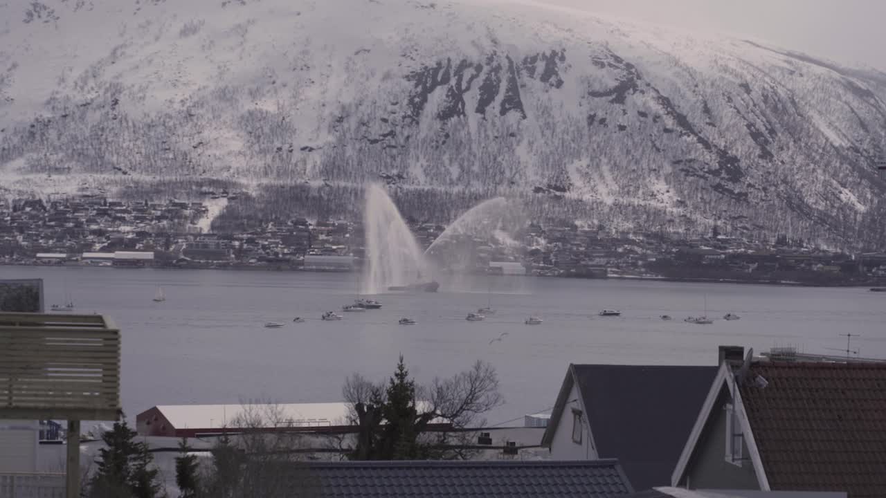 거대한 눈 덮인 산을 배경으로 트롬소에서 노르웨이 제헌절 동안 전통 보트 퍼레이드의 와이드 샷