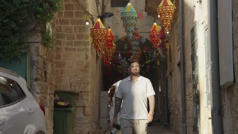 Man-with-camera-walks-into-sunlight-from-old-town-alley-in-Nazareth