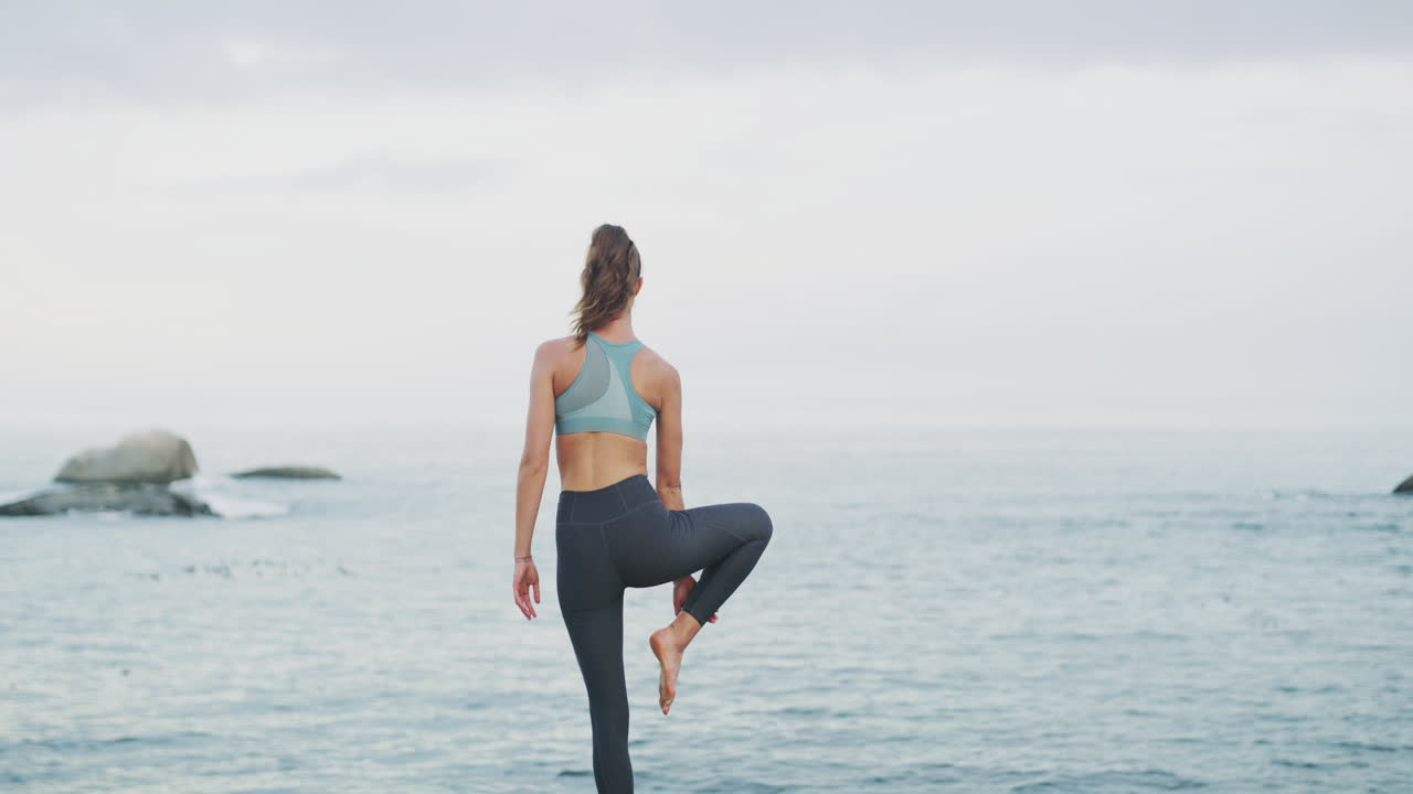 Kvinde der dyrker yoga ved havet