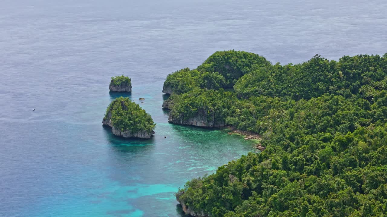 Pan left aerial shot of the Blue Lagoon area showing small forested islets and vibrant blue water.