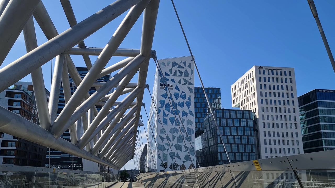 Ponte Akrobaten, passerella pedonale nel centro di Oslo, Norvegia, sopra la stazione ferroviaria con i moderni edifici Barcode sullo sfondo