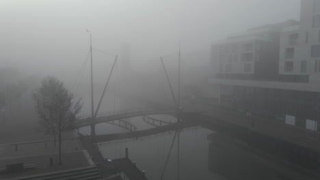 Foque-De-Ciclista-En-Bicicleta-Sobre-Un-Pequeño-Puente-Sobre-El-Río-En-La-Ciudad-Holandesa-Cubierta-De-Niebla