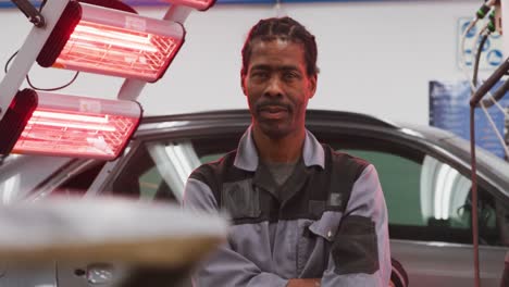 mecánico de automóviles afroamericano cruzando los brazos y mirando a la cámara