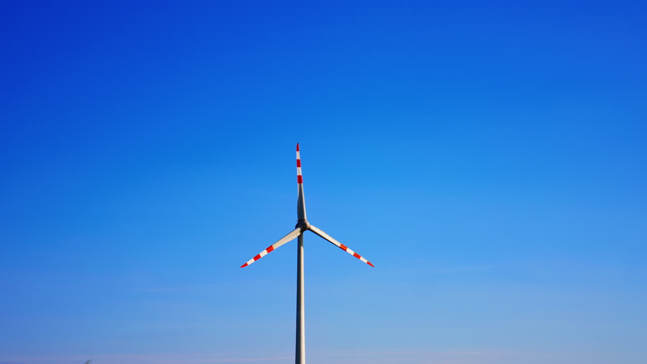 Turbine towers in blue sky. A modern wind turbine is prominently displayed under a bright blue sky, illustrating renewable energy in action