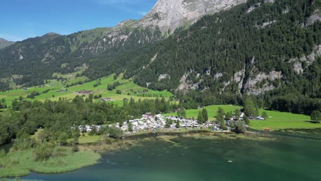 overview of a van camp area for families that went for a holiday trip many white cars and boats close to a clear river in nature in the middle of nowhere paradise on earth gret mountains clear sky