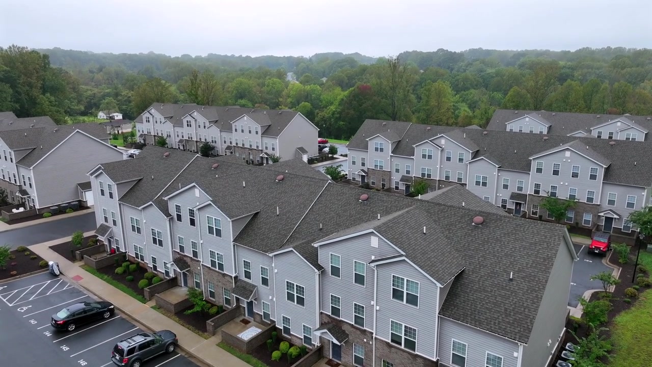 Moderne grå ens huse i et nyudviklet boligområde i USA. Tåget og regnfuld dag i Virginia, USA. Drone-vidvinkelbillede med parkerede biler foran husene