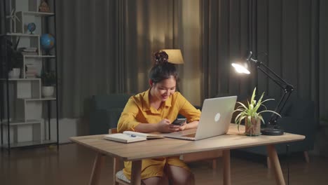 asia woman use smartphone while working from home at living room at night