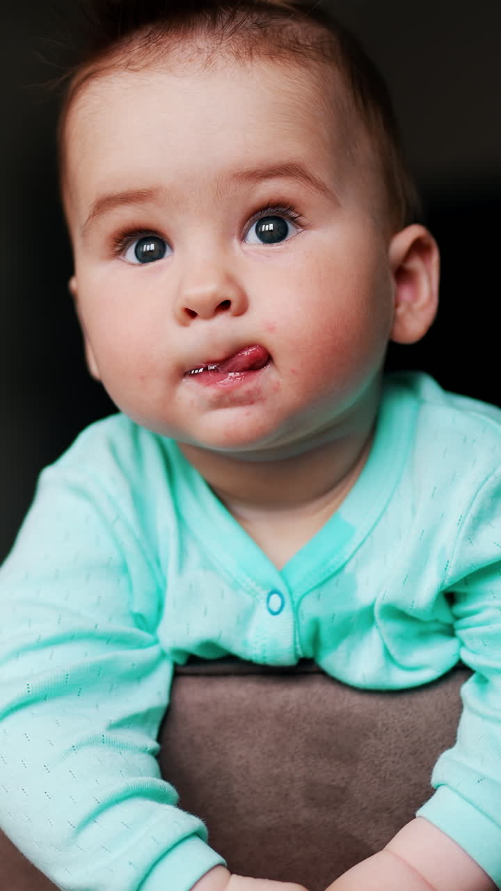 Serious interested kid standing on the chair looks around. Curious baby studying surrounding leaning on a chair back. Low angle view. Vertical video