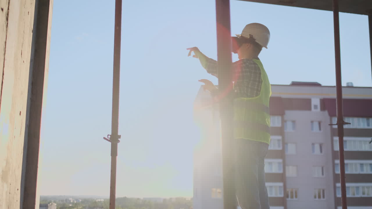 Engineer the Builder on the roof of the building stands in VR glasses and moves his hands using the interface of the future. Futuristic engineer of the future.