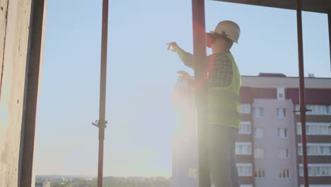 engineer the builder on the roof of the building stands in vr glasses and moves his hands using the interface of the future. futuristic engineer of the future.