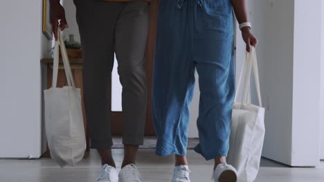 close up of couple carrying reusable cotton shopping bags retuning home