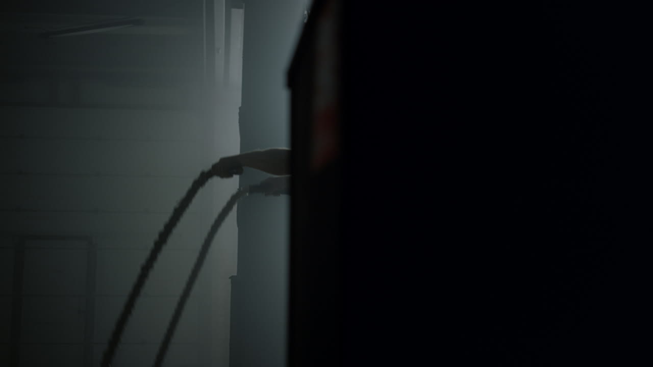 culturista haciendo ejercicios de cuerdas de batalla en el gimnasio. entrenador en forma en el club deportivo