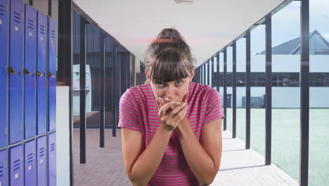 mujer caucásica sonriendo y hablando a la cámara en un pasillo de la escuela secundaria