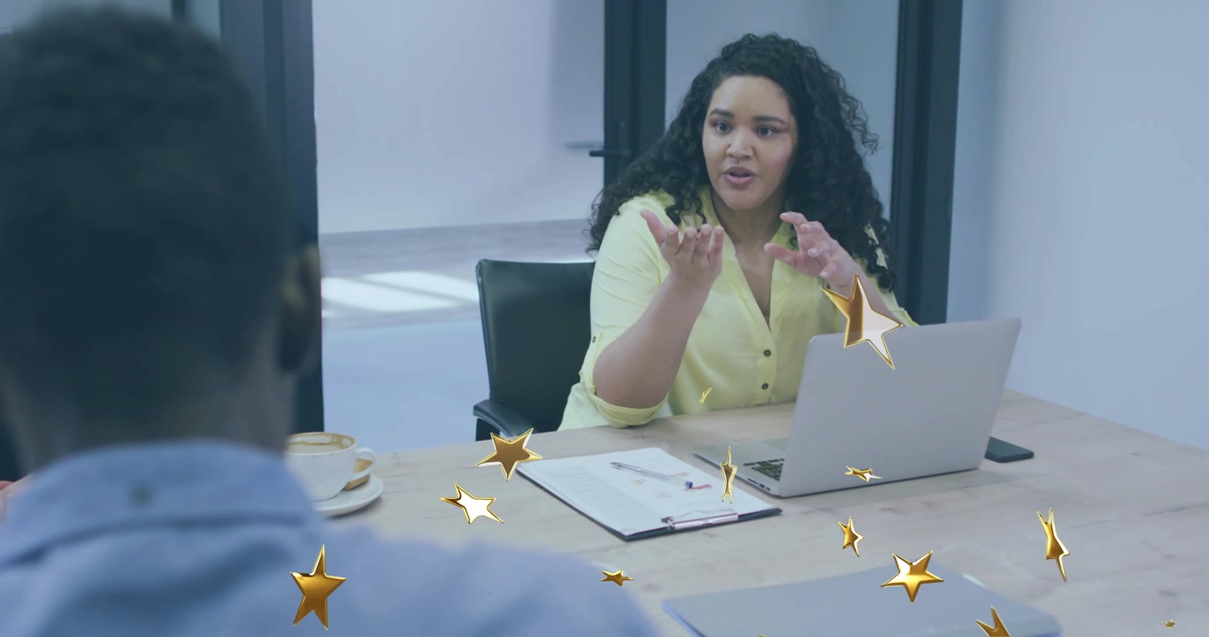 Mulher de amarelo iniciando um briefing, liderando uma reunião de negócios enquanto confetes desaparecem, revelando um laptop.