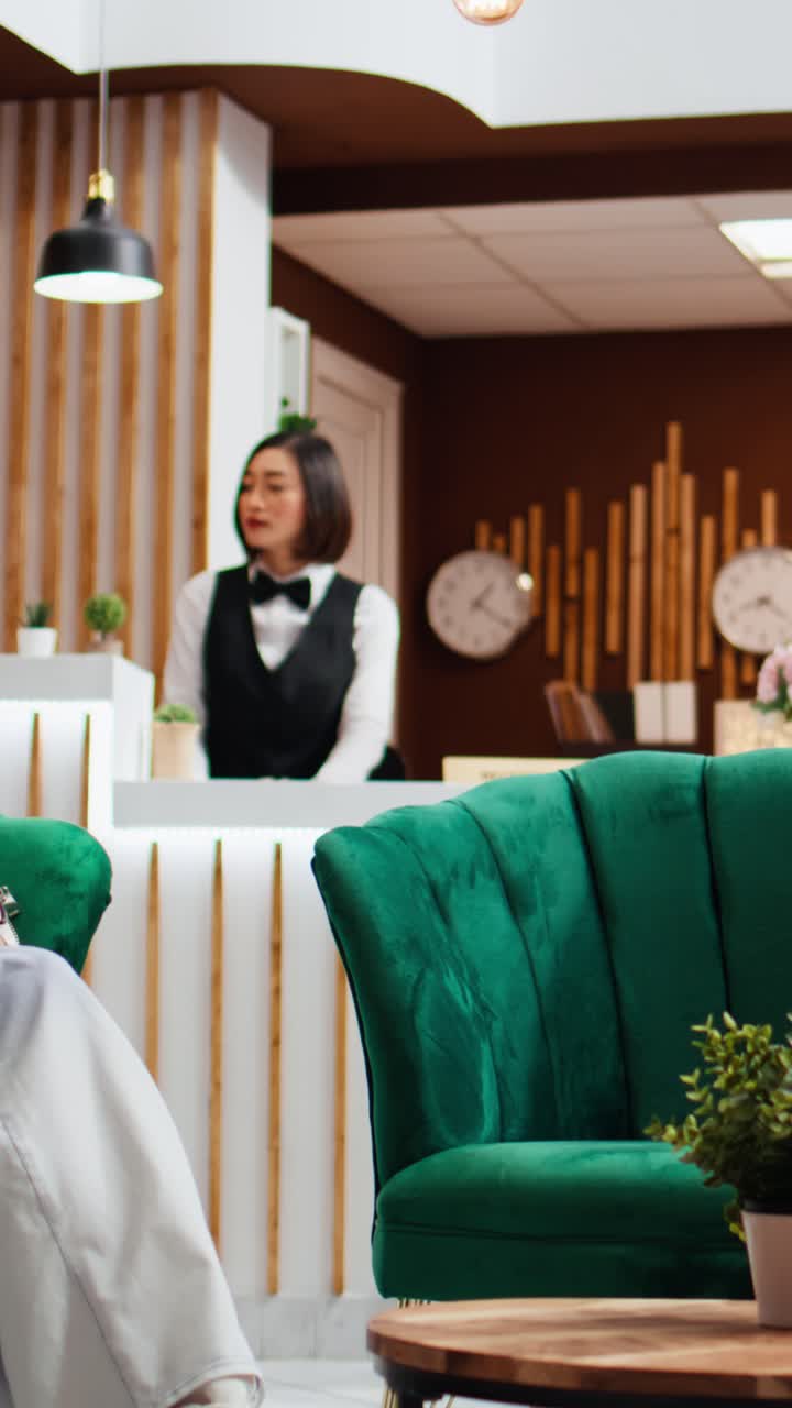 Video verticale di un cameriere asiatico che serve una tazza di caffè a un cliente nella hall