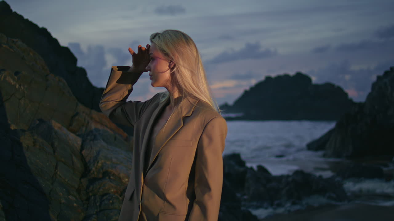 una chica de viaje posando en la costa rocosa en una noche de verano.