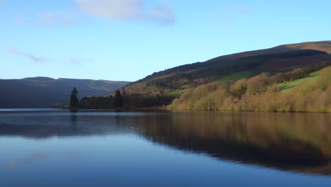 cinematic low level aerial shot tracking over a reservoir in the brecon beacons, wales