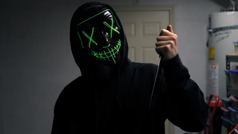 un aterrador asesino slasher con una máscara genérica anónima de terror de halloween tirando un cuchillo a su víctima asesinada