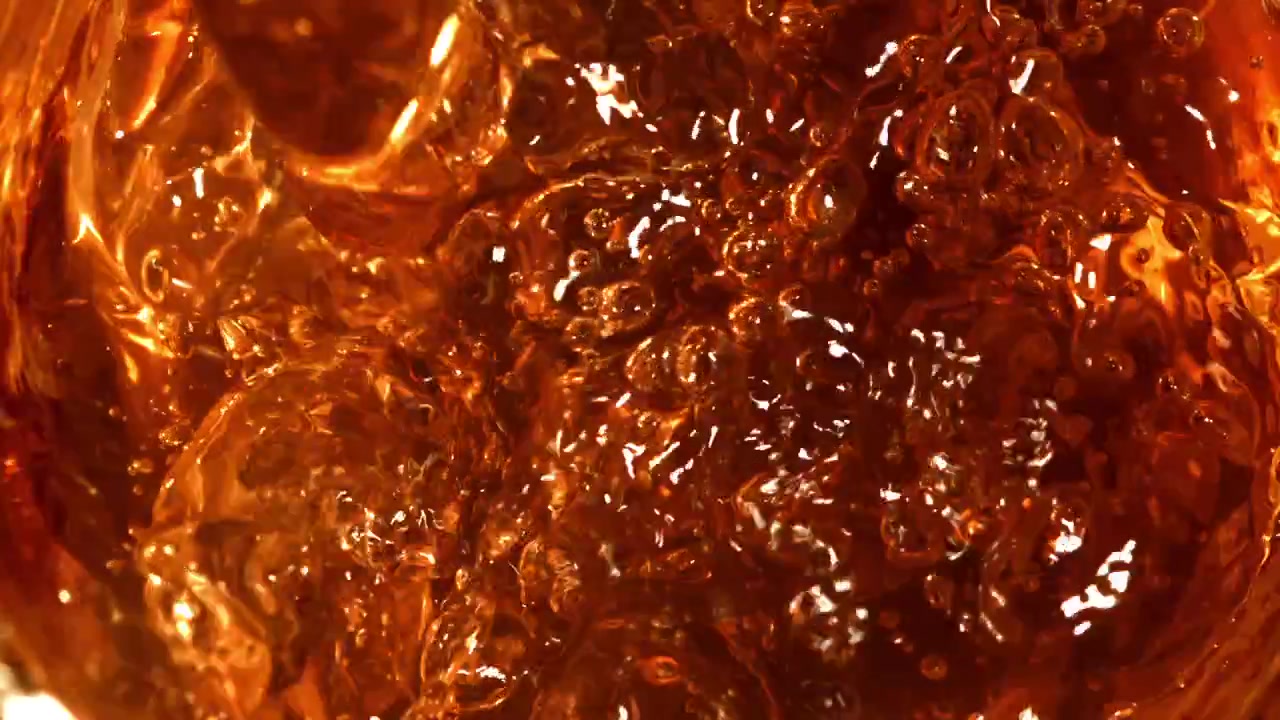 Versamento al rallentatore di liquido ambrato dorato in un bicchiere