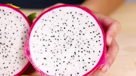 Hands holding and examining dragon fruit halves