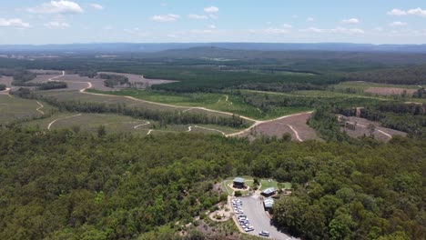 Flying-over-a-carpark-in-the-forest-at-a-lookout-with-fields-and-mountain-at-a-distance