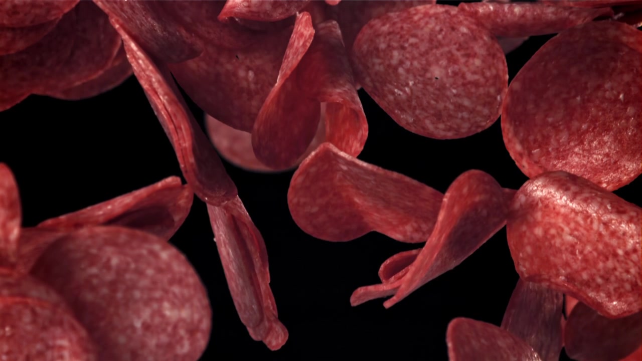 Fette di salame che cadono al rallentatore su sfondo nero