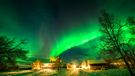 timelapse of green aurora borealis in starry sky in winter over houses, norway