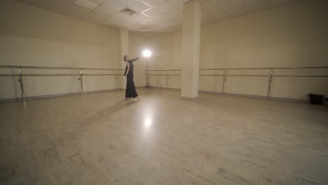 a group of young ballet students in black dancewear practicing positions in a spacious ballet studio with wooden flooring and wall-mounted barres. focused expressions and synchronized movements.