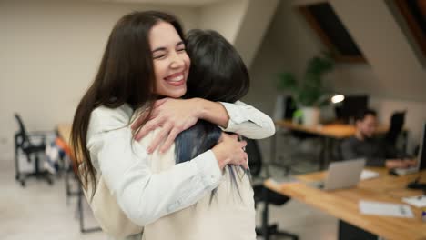 Young-female-office-workers-hugging-to-congratulate-a-colleague-or-missing-a-friend-from-vacation,-slow-motion