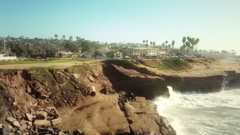 Vuelo-Aéreo-Sobre-Los-Acantilados-Del-Océano-Pacífico-Hacia-Condominios-En-La-Costa-De-San-Diego