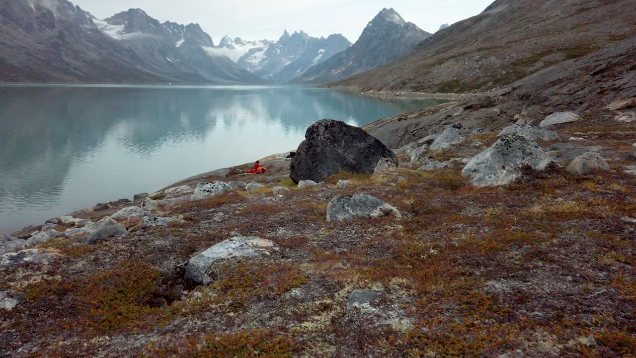 el hombre dentro de la tienda se desabrocha y abre la solapa para revelar un paisaje increíble de fiordos y picos montañosos cubiertos de nieve