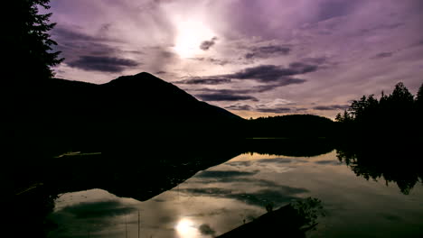 Timelapse-of-Silhouetted-Mountains-and-Reflective-Vibrant-Clouds,-Moon-and-Stars