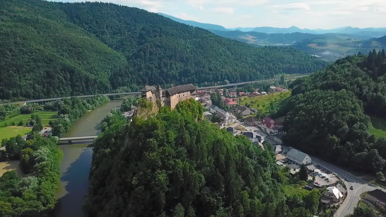 castillo de orava en eslovaquia desde lejos, enfocado en el castillo y el pueblo cercano, orbitándolo y descendiendo, 50fps + 100ss