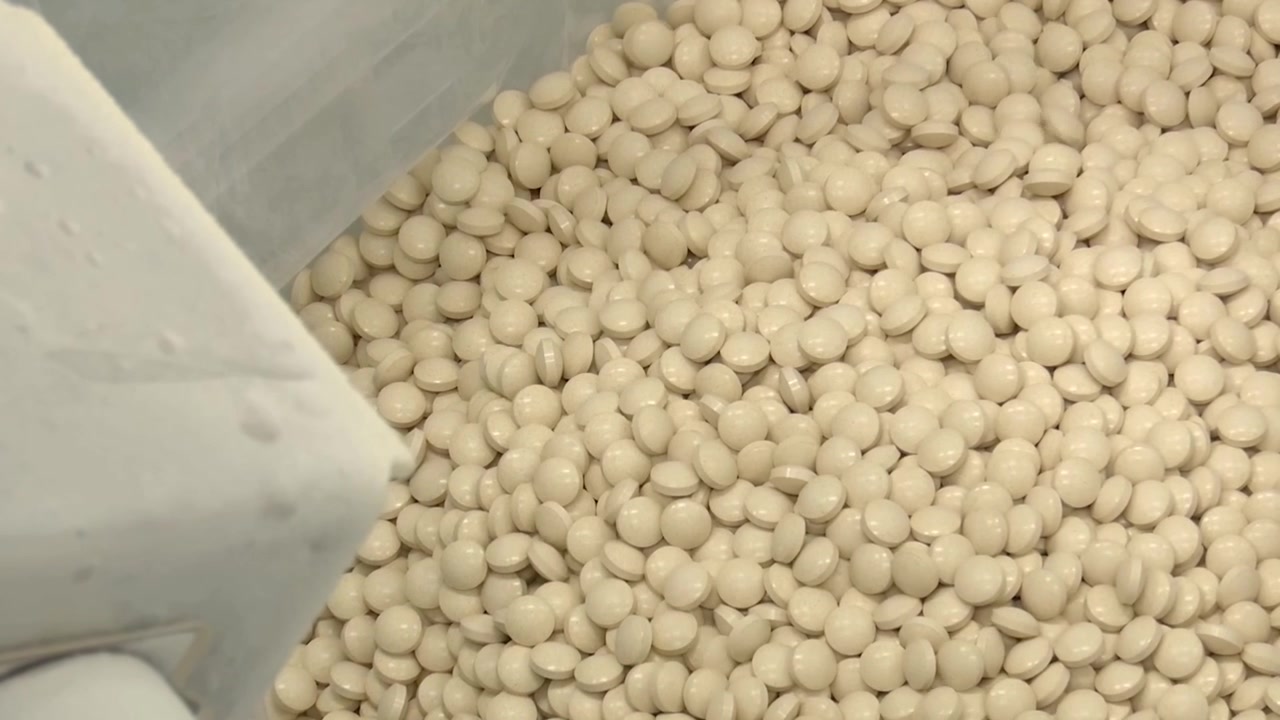 Light yellow drug pills tablets falling down from the machine line in factory.