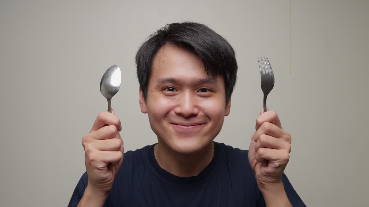 Closeup shot young southeast asian man gets happy lifting fork spoon for eating portrait studio shot