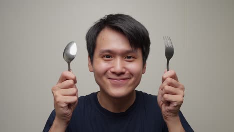 closeup shot young southeast asian man gets happy lifting fork spoon for eating portrait studio shot