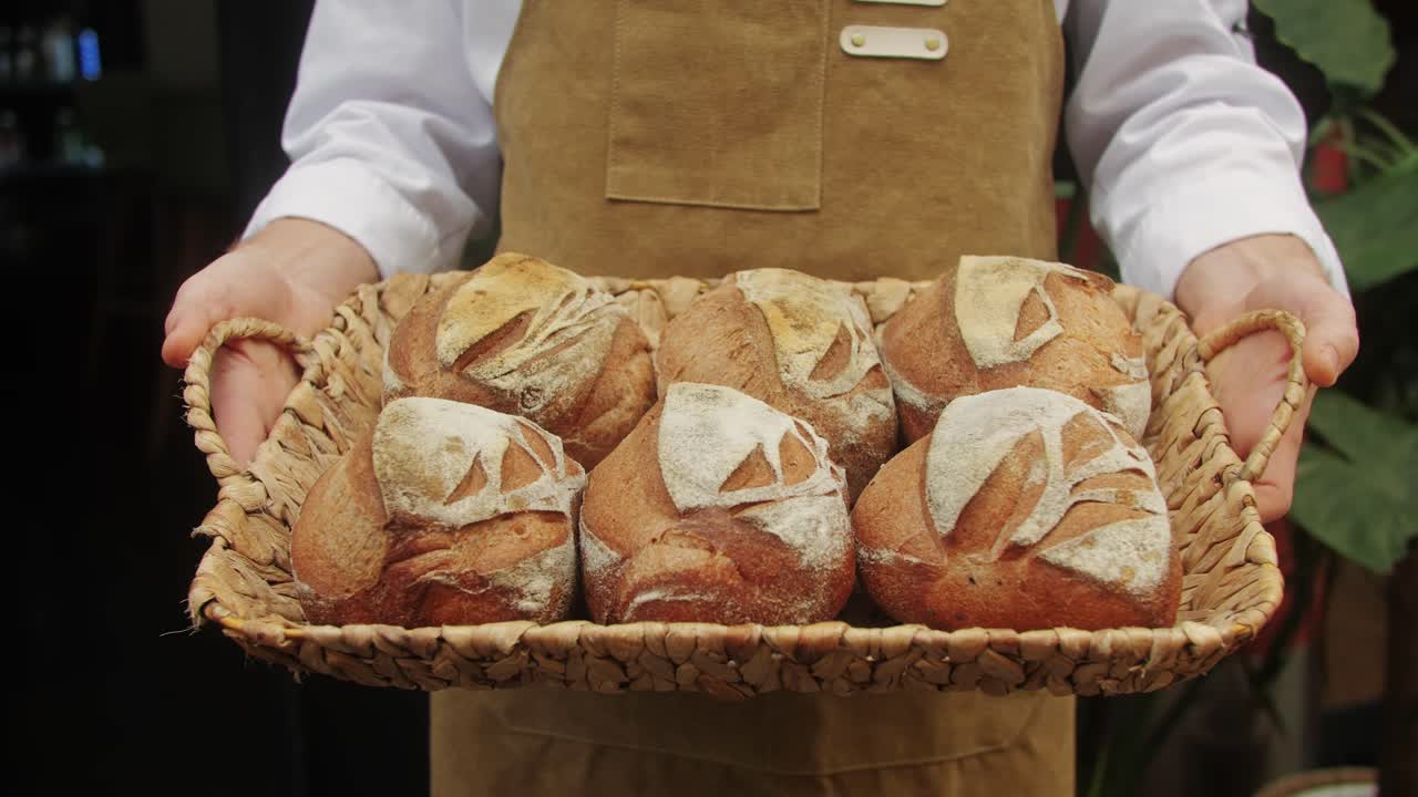 The baker holds in hands a of fresh bread close-up. Artisan bread is making by skill bakers using natural and high-quality ingredients. Food with health and flavour benefits.