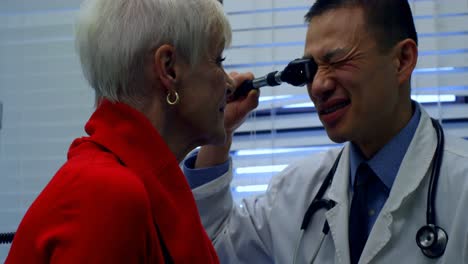 vista lateral de un joven médico asiático examinando a un paciente mayor en la clínica 4k