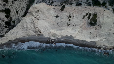 Petra-tou-Romiou-or-Aphrodite's-Rock-Steep-Cliff-Beach-Coastline-in-Paphos,-Cyprus---aerial-top-down-view-at-twilight