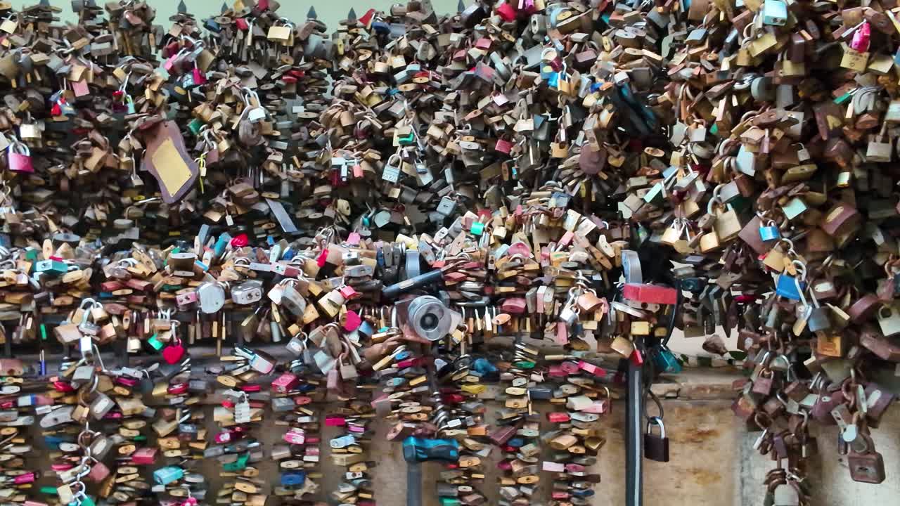 Wide pan shot of a fence covered in countless love locks, symbolizing love and commitment