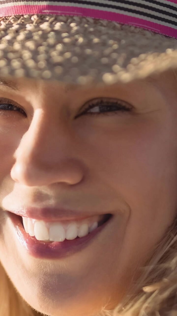 Animation of smiling caucasian woman with hat over falling hats on pink background