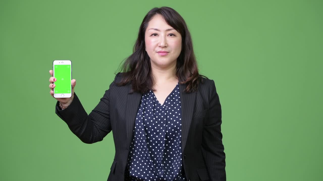 Mature beautiful Asian businesswoman showing phone