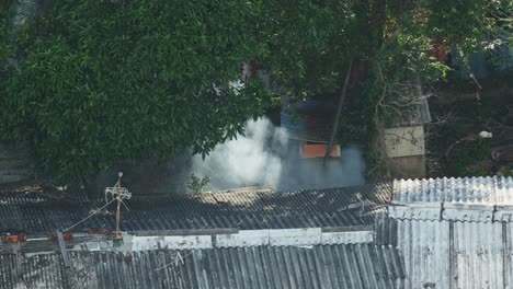 Grey-smoke-rising-at-rural-poor-home-at-day,-aerial-view