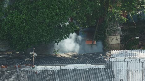 grey smoke rising at rural poor home at day, aerial view