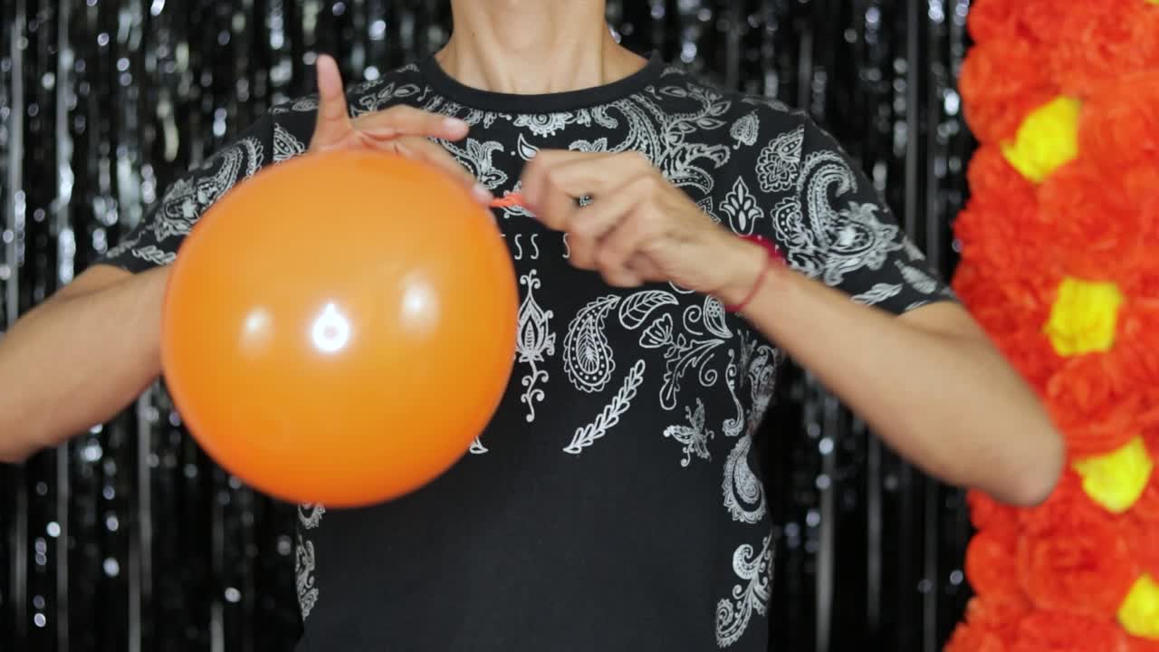atando un globo naranja inflado para la decoración del día de los muertos mexicano