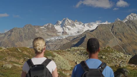 out of focus couple standing in alpine mountains looking at breathtaking landscape